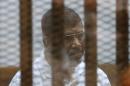 Egypt's deposed Islamist president Mohamed Morsi sits inside the defendant's cage during his trial at the police academy in Cairo on August 18, 2014