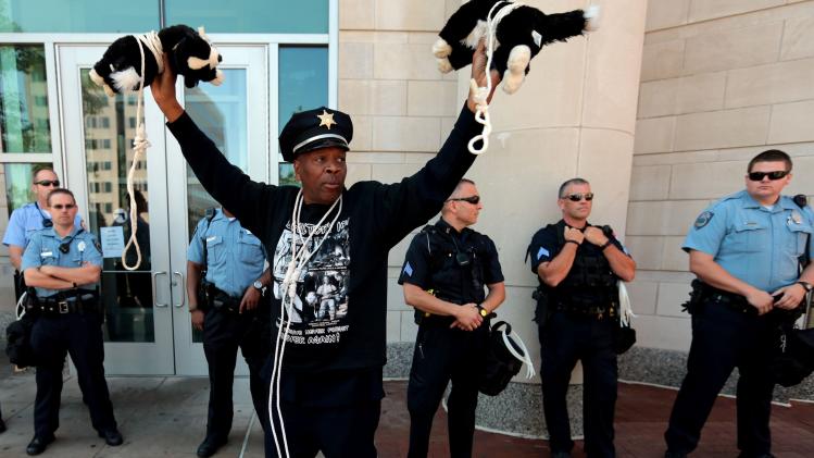 Activist Anthony Shahid holds up two stuffed dogs which he wore around his neck during a rally across the Justice Center, Tuesday, Aug. 12, 2014, in Clayton, Mo., demanding justice for Michael Brown Jr. who was fatally shot by a Ferguson police officer last Saturday. Shahid said &quot;police have more respect for dogs than they do for black people.&quot; (AP Photo/St. Louis Post-Dispatch, Laurie Skrivan)