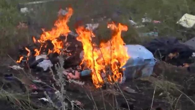 In this image taken from video, Thursday July 17, 2014, showing flames rising from part of the wreckage of a passenger plane carrying 295 people after it was shot down Thursday as it flew over Ukraine