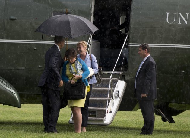 Obama comparte su paraguas con Valerie Jarrett y Anita Decker Breckenridge. (AP Photo/Carolyn Kaster)