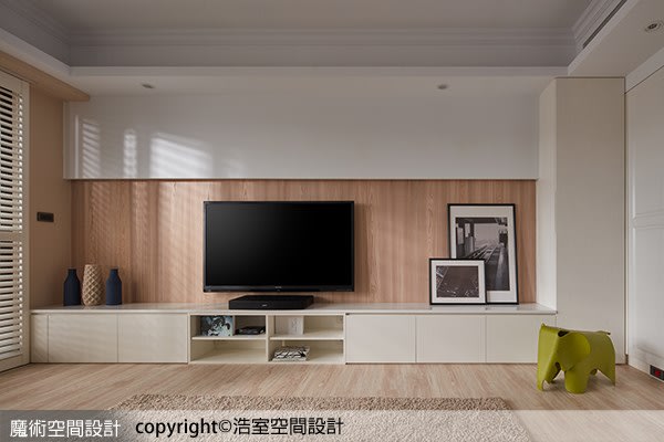 客廳電視牆使用實木木皮，不僅與木地板相呼應，也再次強化溫暖親切的視覺印象。電視櫃本身也是收納櫃，進一步滿足屋主的置物需求。