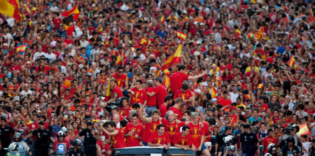 MADRID, SPAIN - JULY 02:  Spain players celebrate with their fans and the UEFA EURO 2012 trophy on a double-decker bus during the Spanish team's victory parade on July 2, 2012 in Madrid, Spain. Spain beat Italy 4-0 in the UEFA EURO 2012 final match in Kiev, Ukraine, on July 1, 2012.  (Photo by Pablo Blazquez Dominguez/Getty Images)