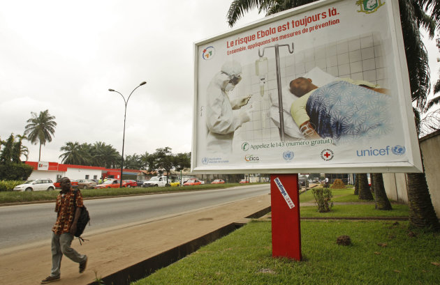 A man, left, walk past a Ebola awareness campaign poster, in the city of Abidjan, Ivory Coast, Monday, Aug. 25, 2014. (AP Photo/Sevi Herve Gbekide )