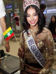 FILE - In this June 5, 2014 file photo, Myanmar model May Myat Noe, winner of Miss Asia Pacific World 2014 pageant, waves a miniature flag of the country upon her arrival at Yangon International Airport in Yangon, Myanmar. The first Myanmar national to win an international pageant has been stripped of her title for being rude and dishonest, and has allegedly run off with the expensive crown and breast implants. (AP Photo/Khin Maung Win)