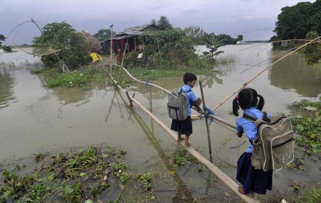 Niños indios utilizando un puente de bambú para cruzar una zona inundada de Morkata, el 25 de agosto de 2014. Las inundaciones y deslizamientos de tierra han dejado casi 200 muertos y una cifra superior de desaparecidos