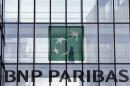 An employee walks behind the logo of BNP Paribas in a   company's building in Issy-les-Moulineaux, near Paris