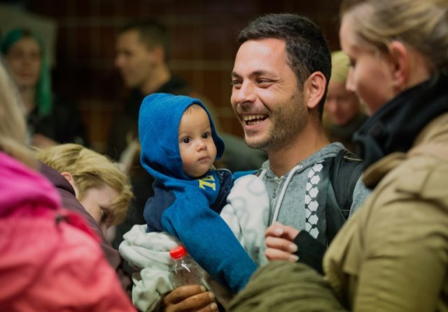 Migrante sorri após ser cumprimentado pela população local ao desembarcar na estação ferroviária de Hamburgo, Alemanha,