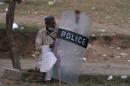 A supporter of opposition leader Qadri holds a police   shield as he sits along a road in Islamabad