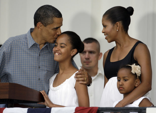 FILE - This July 4, 2009, file photo shows President Barack Obama, left, as he kisses his daughter Malia Obama, 11, as his daughter Sasha Obama, 7, and his wife Michelle Obama stand right, during a Fourth of July party on the South Lawn of the White House in Washington. President Obama is practically weepy at the thought of his daughter Malia going off to college, a milestone many months away that is on his mind now. At 16, she stands nearly as tall as her 6-foot-1 dad and is visiting college campuses in preparation for that bittersweet day in the fall of 2016 when she trades her White House bedroom for a dorm. (AP Photo/Alex Brandon, File)