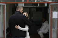 Bosnian woman Denisa Hegic hugs her husband as she enters at the Sejkovaca identification center, near the Bosnian town of Sanski Most, 260 kilometers (162 miles) northwest of Sarajevo ,on Wednesday, April 16, 2014. Denisa Hegic was eight when Serb soldiers stormed her house and killed her entire family at the beginning of the 1992-95 Bosnian war. An aunt pulled her away from her mother's bloody body and they tried to run away, were caught but escaped again. After 22 years, Hegic reunited with her family on Wednesday at the freezing mortuary where the remains of hundreds of Muslim Bosniaks killed during the Bosnain Serb ethnic killings campaign are stored after they were excavated from Bosnia's biggest mass grave.(AP Photo/Amel Emric)