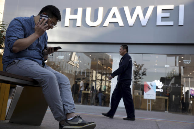 Un hombre utiliza dos smartphones al mismo tiempo fuera de una tienda Huawei en Beijing el lunes 20 de mayo de 2019. (AP Foto/Ng Han Guan)