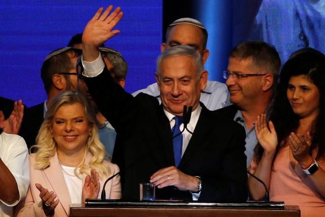 Israeli Prime Minister Benjamin Netanyahu stands next to his wife Sara as he waves to supporters at his Likud party headquarters following the announcement of exit polls. (REUTERS)