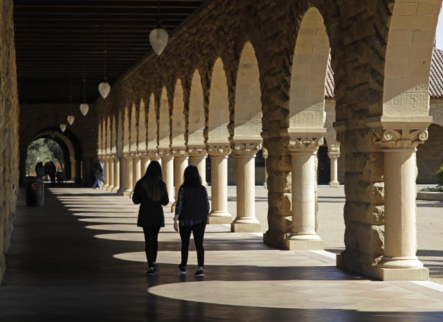 FILE- In this March 14, 2019, file photo students walk on the Stanford University campus in Santa Clara, Calif. Before student loans, people who couldn’t afford to go to college usually didn’t. Even though tuition was cheaper, it was still cost-prohibitive for many, who turned to solutions such as working through school, getting help from their parents or finding scholarships. (AP Photo/Ben Margot, File)