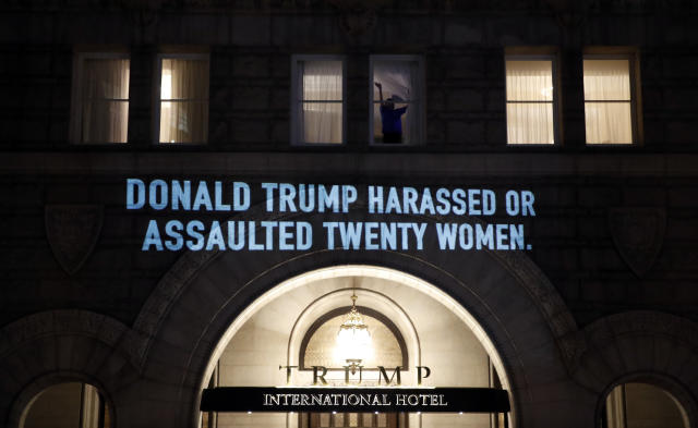 A person waves from a window as UltraViolet, a national women's group, projects a message on the 12th Street side of the Trump International Hotel before President Donald Trump gives his State of the Union Address, in Washington Trump State of Union Protest, Washington, USA - 30 Jan 2018
