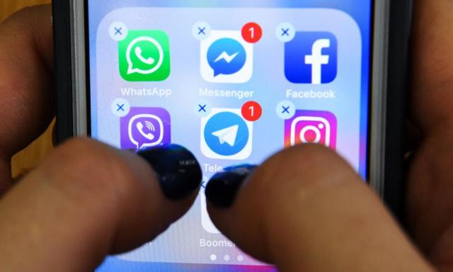 A woman holds a phone with the icons for the social networking apps Facebook, Instagram and others